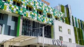 A building with a green and white facade, a sign reading 'Wisata Naga', and a 'WN Cafe' entrance. - Hotel Wisata Niaga (Purwokerto)