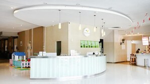 Una moderna zona de recepción con un mostrador curvo, iluminación colgante y un área de juegos para niños.