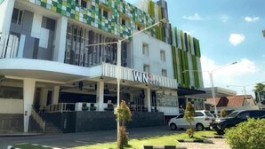 Un edificio de varios pisos con fachada verde y blanca, una entrada visible y un letrero que dice 'WISATA Niaga'.