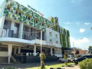 A multi-story building with a green and white facade, a visible entrance, and a sign that reads 'WISATA Niaga.' - Hotel Wisata Niaga (Purwokerto)