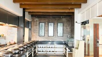 A modern kitchen with a long counter, a brick wall, and a wooden ceiling.