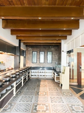 A modern kitchen with a long counter, a brick wall, and a wooden ceiling. - Hotel Wisata Niaga (Purwokerto)
