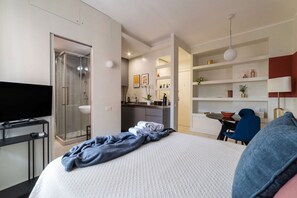 Une chambre d’hôtel moderne équipée d’un lit, d’une télévision, d’une douche, d’une kitchenette et d’un coin repas.