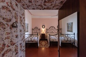 A bedroom with two beds, a nightstand, a wall clock, and a ceiling fan.