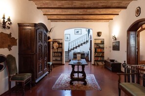 A spacious living room with a wooden floor, a large wooden cabinet, a table with a vase, and a staircase leading to another level.