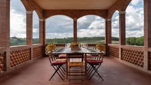 Un espace extérieur aménagé pour les repas, avec une arche en briques, une table dressée pour quatre personnes et une vue sur le paysage.