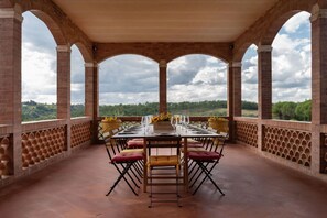 Un espace extérieur aménagé pour les repas, avec une arche en briques, une table dressée pour quatre personnes et une vue sur le paysage.