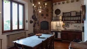 Eine Küche mit Steinwand, Kamin und Essbereich mit Tisch und Stühlen.
