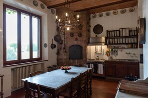 Una cucina con parete in pietra, un camino e un'area pranzo con tavolo e sedie.