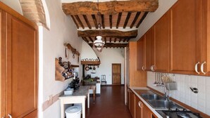 Une cuisine étroite avec des meubles de rangement en bois, une cuisinière à gaz et un luminaire suspendu.
