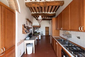Una cucina modesta con pensili in legno, un fornello a gas e un lampadario.