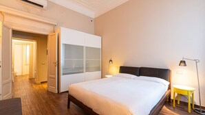 Een slaapkamer met een bed, een kledingkast en een nachtkastje met een lamp.