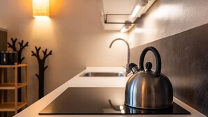 Een moderne keuken met een zwart inductiekookveld, een roestvrijstalen waterkoker en een witte spoelbak.