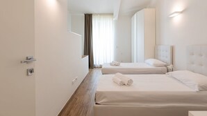 A hotel room with two beds, a wooden floor, a large window with curtains, and built-in wall lighting. - Beautiful two bedrooms Navigli - Mirable PM (Milano)