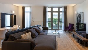 A modern living room with a large sectional sofa, a small round coffee table, and a television on a wooden stand. - Beautiful two bedrooms Navigli - Mirable PM (Milano)
