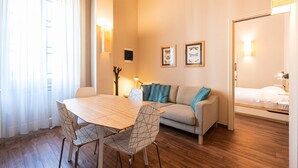 Una sala moderna con una mesa de comedor de madera, dos sillas, un sofá y una cama.