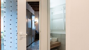 A narrow hallway leading to a bathroom with a checkered floor, a sink, and a window with blinds. - One bedroom Corso Garibaldi - Mirable PM (Milano)