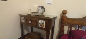 A wooden bedside table with a kettle, a glass, and a tray. - Namaste Yoga Farm (Kumta)