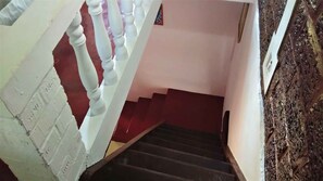 A staircase with white balusters, a red wall, and a dark floor.