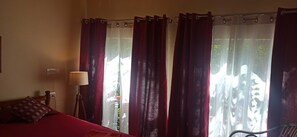 A room with a bed, a lamp, and a window with curtains. - Namaste Yoga Farm (Kumta)