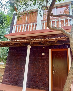 A two-story building with a balcony, a door, and a tree in the foreground.