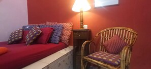 A room with a bed, a chair, a lamp, and a wall-mounted light switch.
