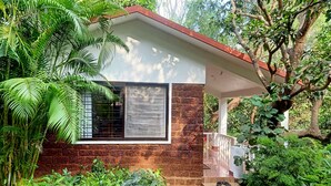 Ein kleines Haus mit Backsteinmauer, einem Fenster mit Gitterstäben und einer Veranda.