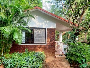 A small house with a brick wall, a window with metal bars, and a porch. - Namaste Yoga Farm (Kumta)