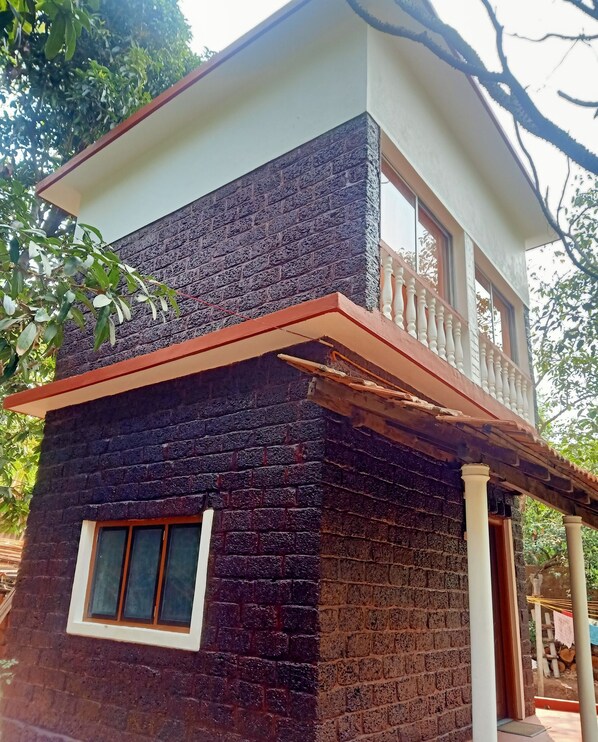 Un edificio de dos pisos con un balcón, una ventana y fachada de ladrillo.