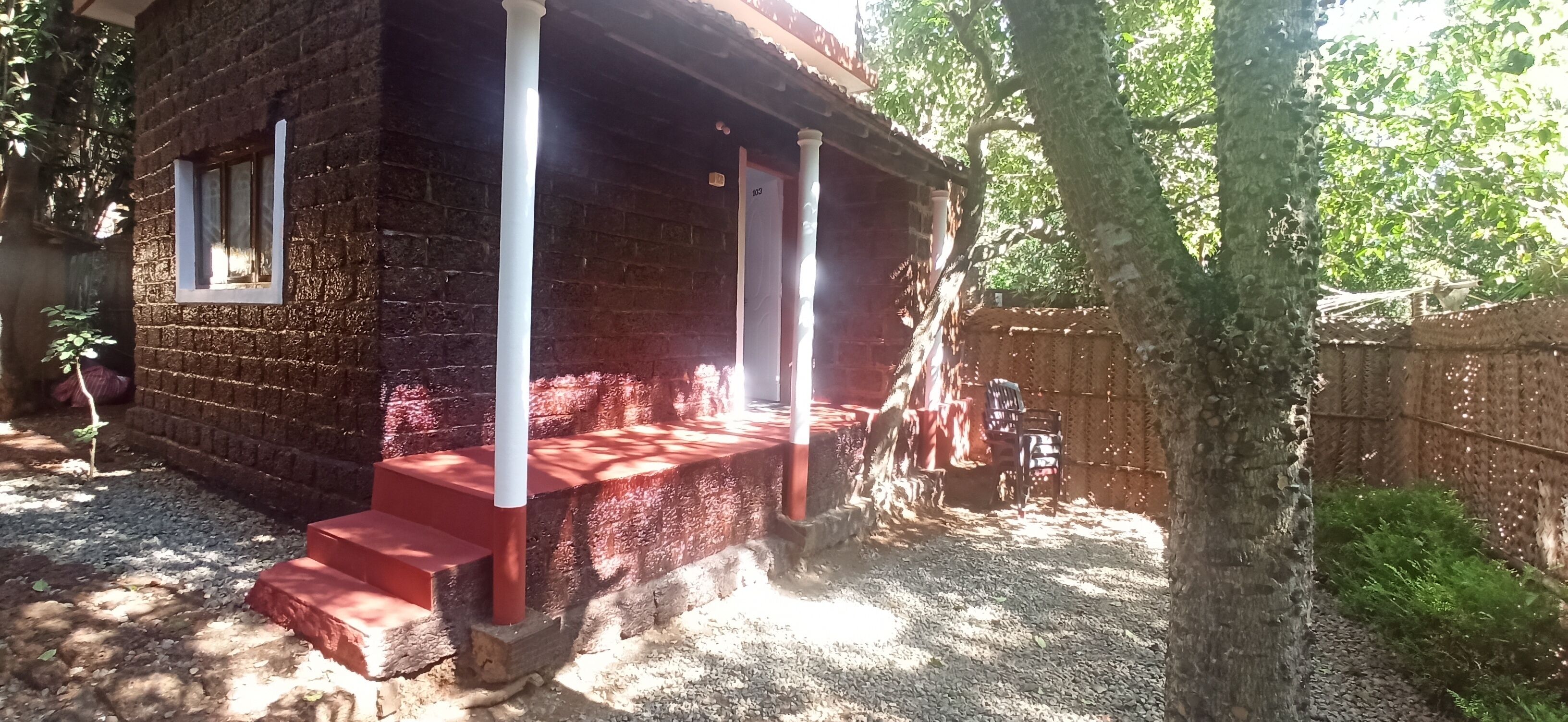 Una cabaña de madera rústica con un porche, escalones y un patio cercado.
