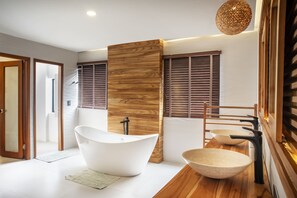 Een moderne badkamer met een vrijstaand bad, een houten wastafelmeubel en een grote waskom.