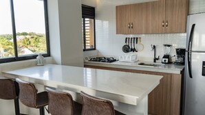 A modern kitchen with a large island, wooden cabinets, and stainless steel appliances.