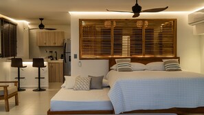 Een slaapkamer met een bed, nachtkastjes, een bureau en een kitchenette.