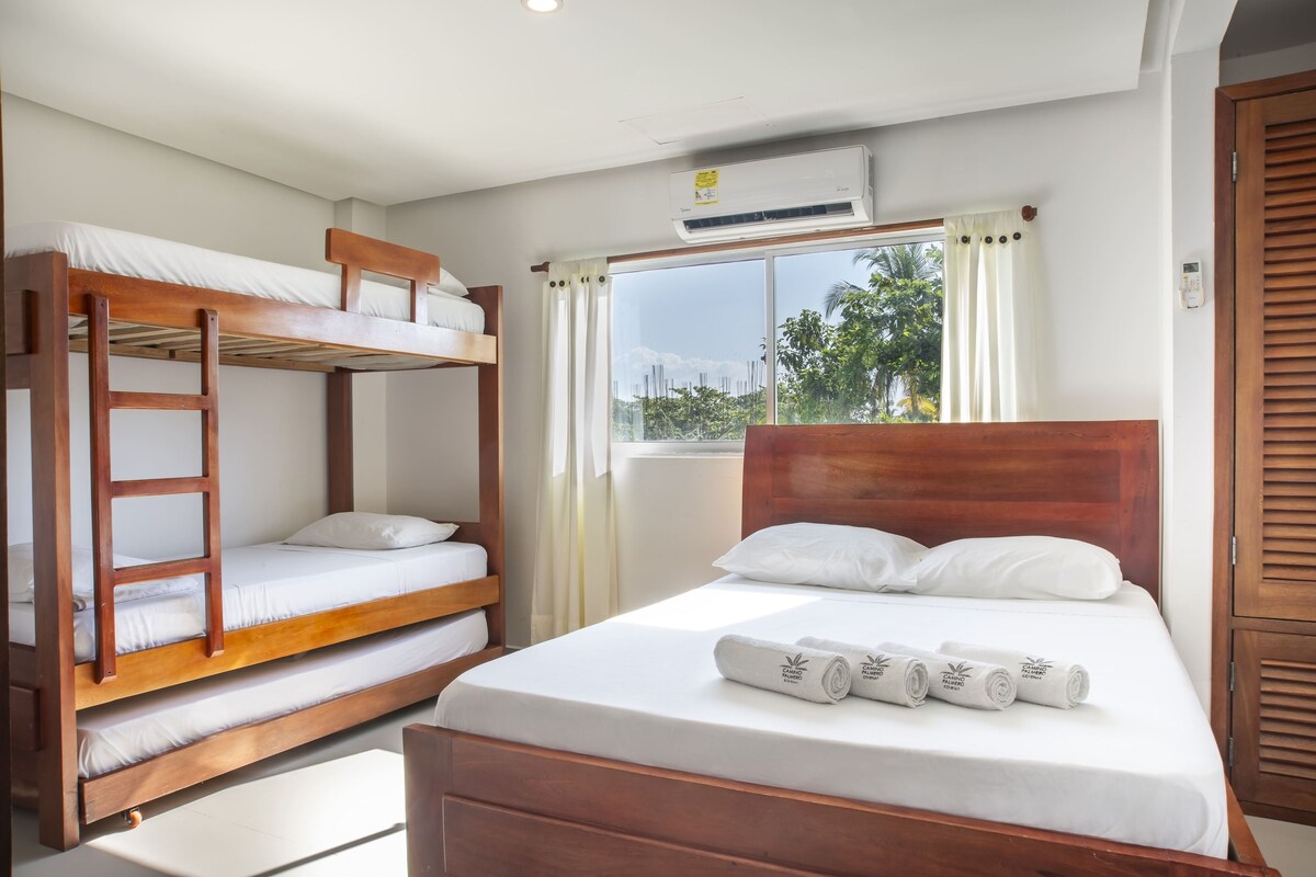Een kamer met een stapelbed, een eenpersoonsbed en een raam met gordijnen.