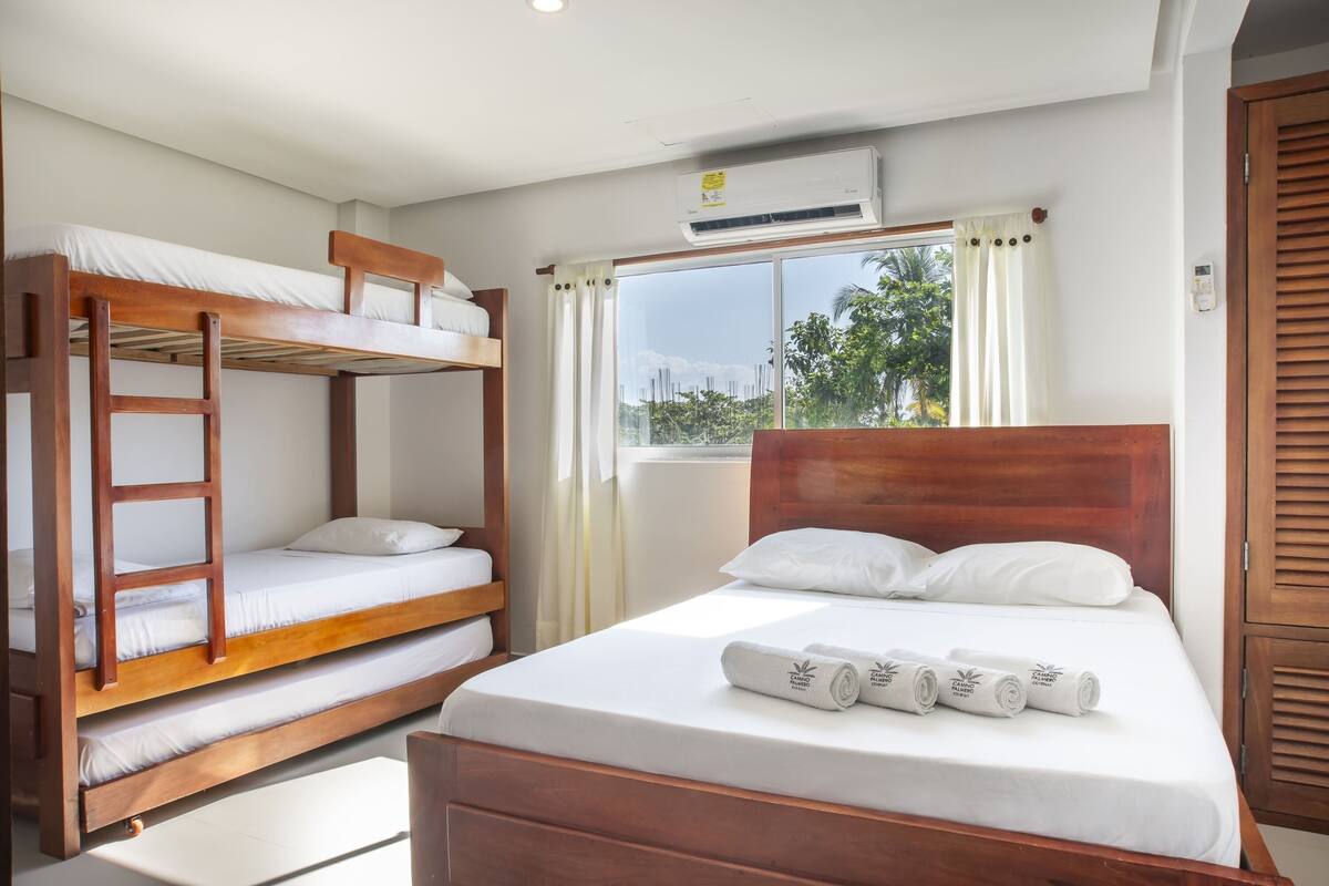 Ein Zimmer mit Etagenbett, Einzelbett und einem fenster mit Vorhängen.