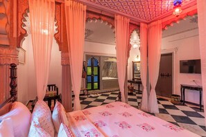 A traditional room with a bed, curtains, and a checkered floor. - Indulge Udaipur By Pack (Udaipur)