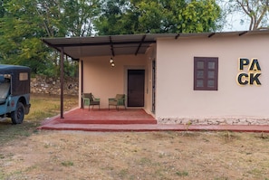 A building with a covered porch, two chairs, a door, and a wall with 'PACK' written on it. - Indulge Udaipur By Pack (Udaipur)