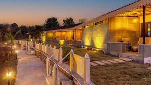 Un hotel con un camino de piedra que conduce a la entrada, un área de estar al aire libre techada y una fachada bien iluminada.