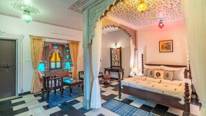 Una habitación tradicional con suelo a cuadros, cama con dosel y un arco decorativo.