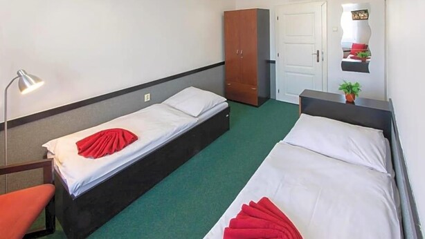 A hotel room with two single beds, a desk, a chair, a wardrobe, and a mirror. - Masarykova Kolej (Prague)