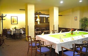 Comedor con una larga mesa dispuesta para una comida, rodeada de sillas de madera con cojines azules.