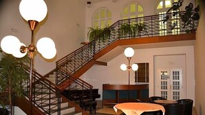 Un interior a diversos nivells amb escala, un piano, una recepció i una zona de dinar.