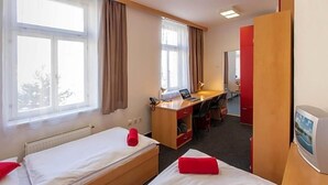 A hotel room with two single beds, a desk, a chair, and a television. - Masarykova Kolej (Prague)