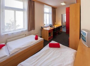 A hotel room with two single beds, a desk, a chair, and a television. - Masarykova Kolej (Prague)
