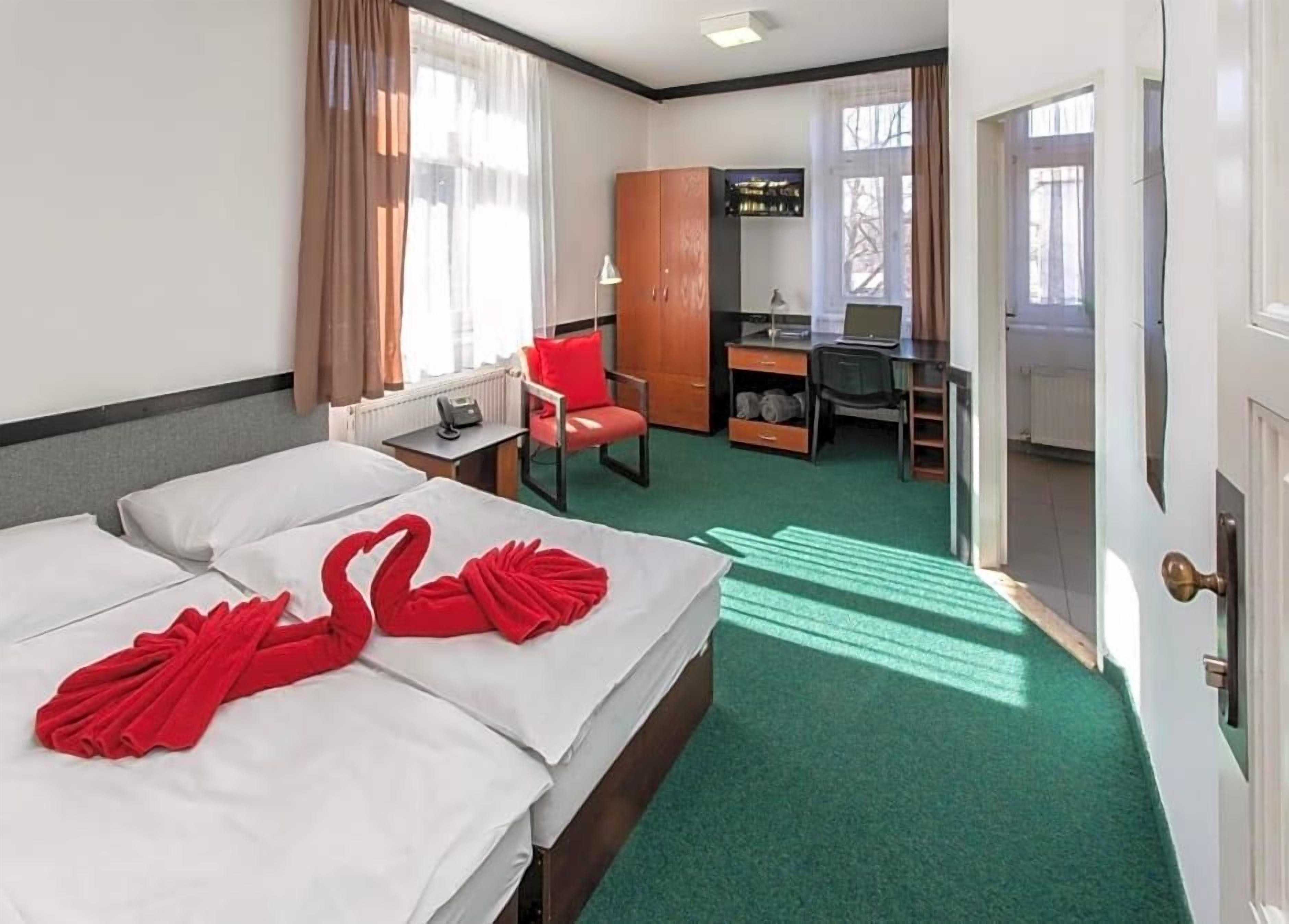 Habitación de hotel con dos camas, un escritorio, una silla y un armario.