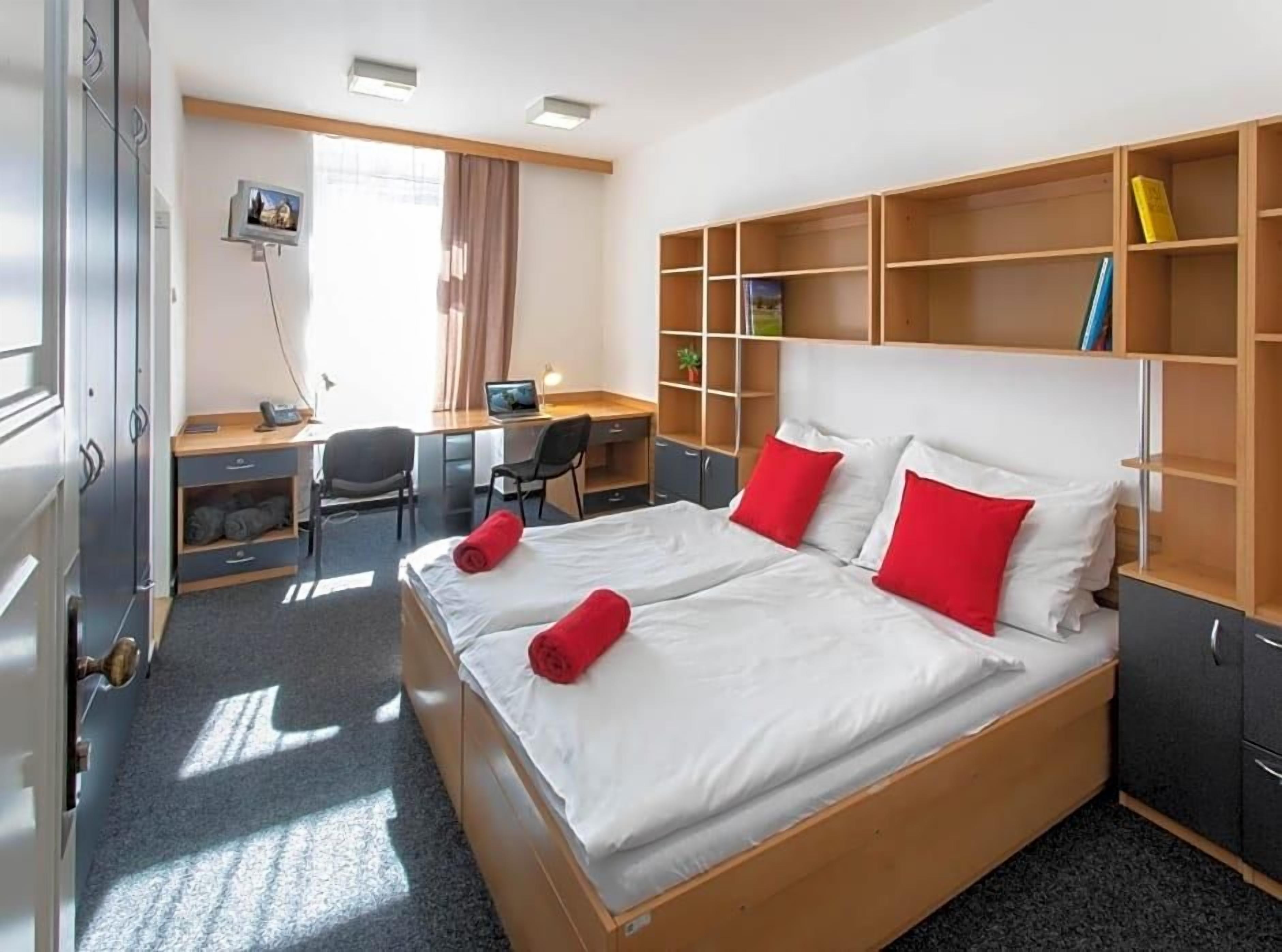 Une chambre d’hôtel avec un grand lit, un bureau, une chaise et une armoire.
