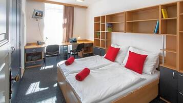 Una habitación de hotel con una cama grande, un escritorio, una silla y un armario.