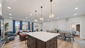 Une cuisine spacieuse dotée d’un grand îlot central, de meubles en bois et de luminaires suspendus.