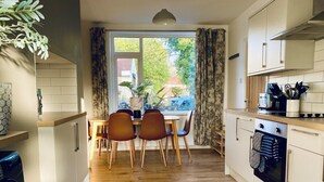Una cocina moderna con piso de madera, un área de comedor con mesa y sillas, y vistas a través de un ventanal.