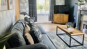 Una sala de estar moderna con sofá, mesa de centro y televisor.